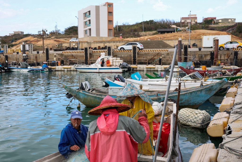 Fishermen work on their boat docked at a port in Kinmen
