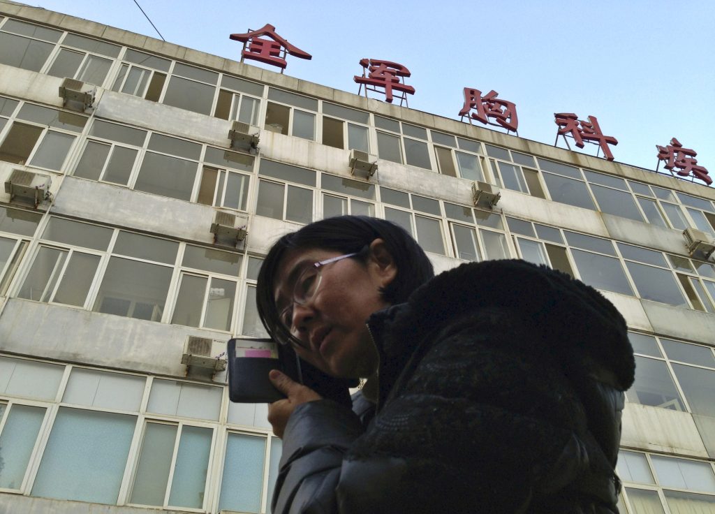 Wang Yu the lawyer of human right activist Cao Shunli talks on the phone in front of a hospital building where Cao is hospitalized at its intensive care unit in Beijing