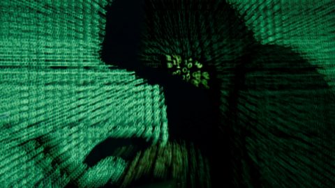 Man holds laptop computer as cyber code is projected on him in this illustration picture