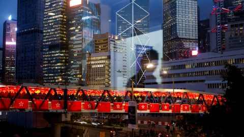 Reflection of a man is seen on the glass while a pedestrian footbridge in the background is adorned with China s and Hong Kong s flags as decorations for the celebration of National Day in Hong Kong