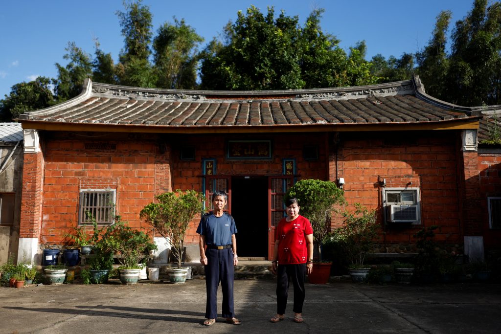 Wei Hsin hsi and his wife pose for a picture outside their family’s temple in Taoyuan