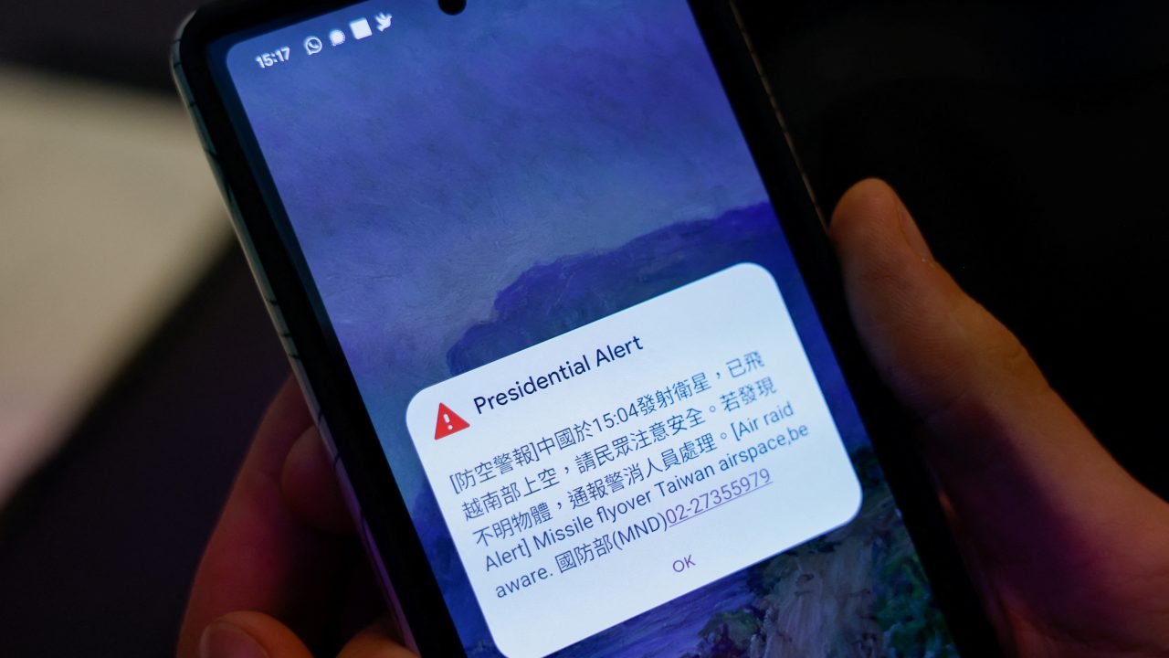 A person attending a Foreign Ministry s news conference holds a phone showing air raid alert about a Chinese satellite