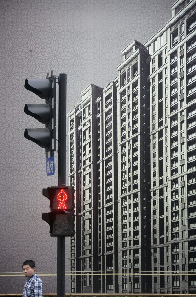 FILE PHOTO: A man walks past a real estate billboard on a street in Hangzhou
