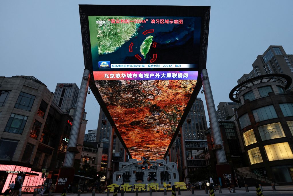 FILE PHOTO: A large screen shows news footage of a map of military drills around Taiwan conducted by the Eastern Theatre Command of the PLA in Beijing