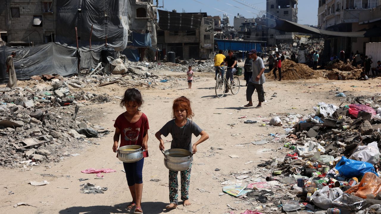 Palestinian children carry pots of soup near a food distribution point in Gaza’s Jabalia refugee camp on August 21. (PhotoL Omar Omar Al-Qattaa /AFP)