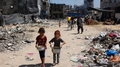 Palestinian children carry pots of soup near a food distribution point in Gaza’s Jabalia refugee camp on August 21. (PhotoL Omar Omar Al-Qattaa /AFP)