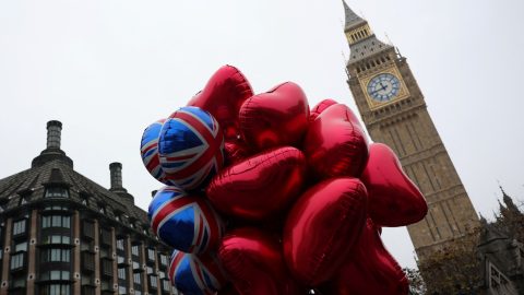 A woman holds a cluster of balloons near Big Ben in London. (Photo: Isabel Infantes/Reuters)