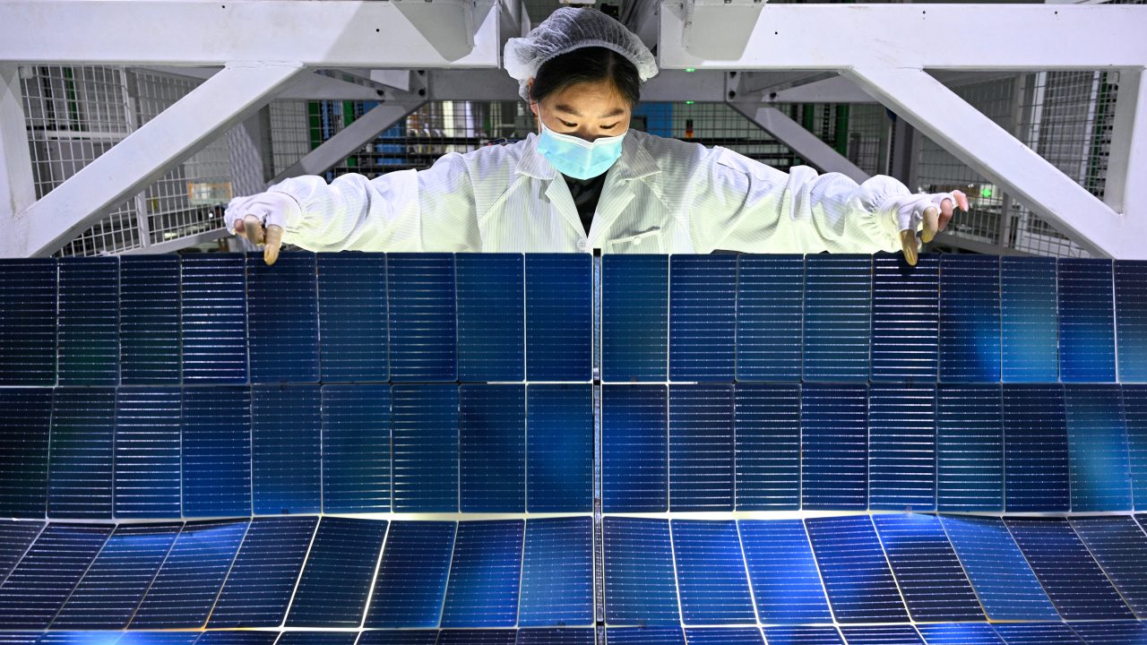 A worker holds photovoltaic modules for solar panels in a factory in China’s Jiangsu Province. (Photo: AFP)