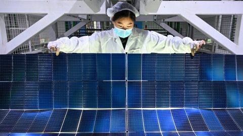 A worker holds photovoltaic modules for solar panels in a factory in China’s Jiangsu Province. (Photo: AFP)