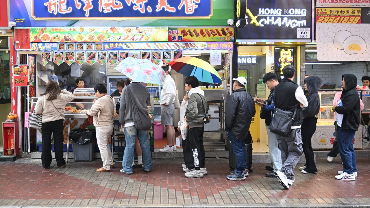 People line up outside a restaurant in Hong Kong in February. (Photo by Peter Parks/AFP)